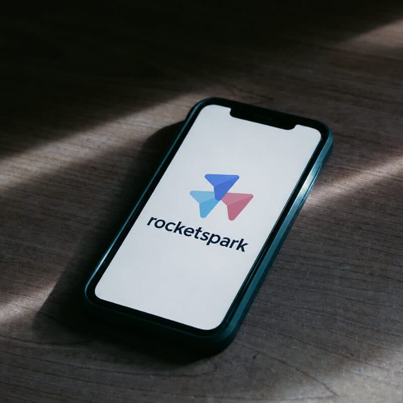 A smartphone showing the Rocketspark logo, lying on a wooden desk