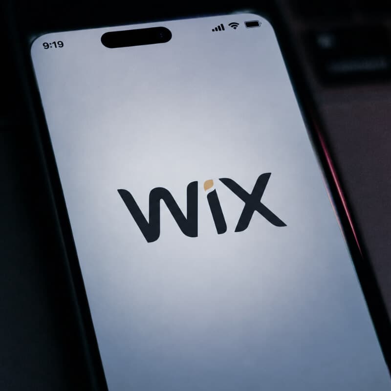 A smartphone showing the Wix logo, on a desk beside a laptop keyboard