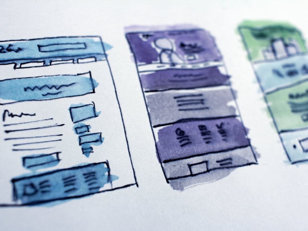 Hand-drawn watercolour sketches of website page layouts on paper, in blue, purple and green